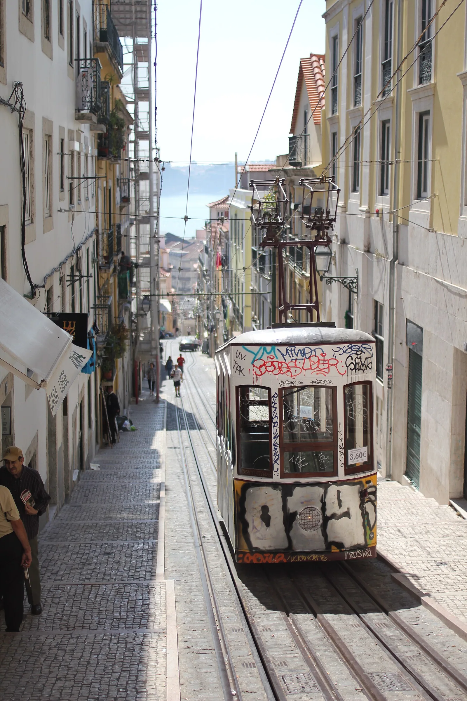 Lisbon rooftops and the Tagus river beyond, with terracotta tile roofs in the foreground